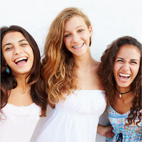 Mädchen lachen gemeinsam vor hellem Hintergrund